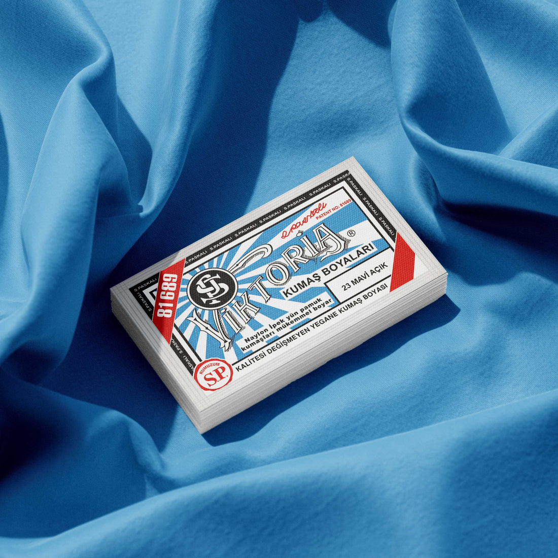 Pack of ice blue fabric dye placed on a vibrant light blue fabric background